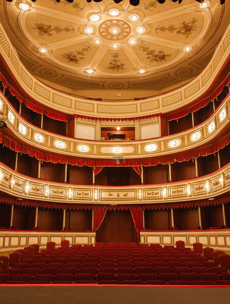 Klassisches Theater mit rotem Bühnenvorhang mit Bogenlichtern und Schatten. Blick von der Bühne | © Gettyimages.com/Avatar_023