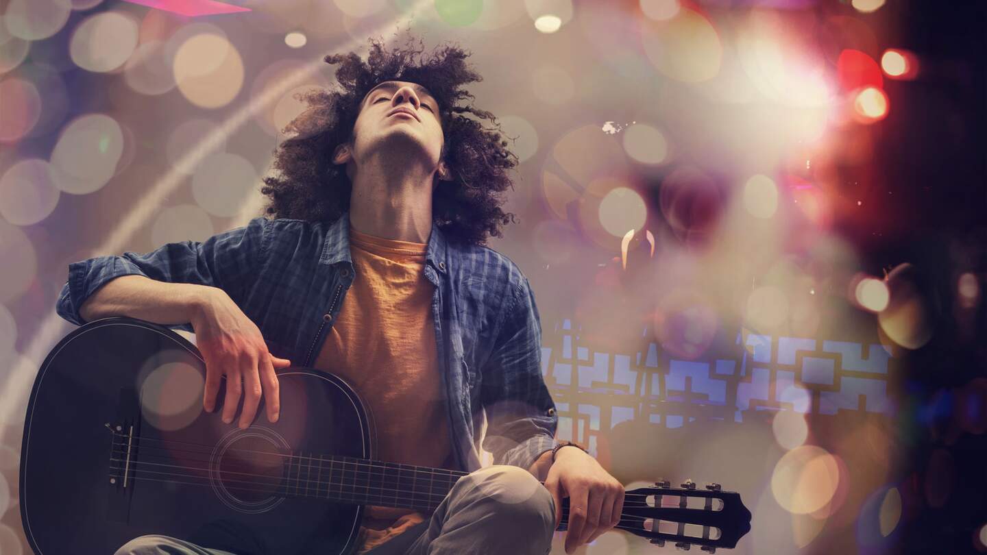 Junger Mann spielt Gitarre vor künstlerischem Hintergrund | © Gettyimages.com/seb_ra 