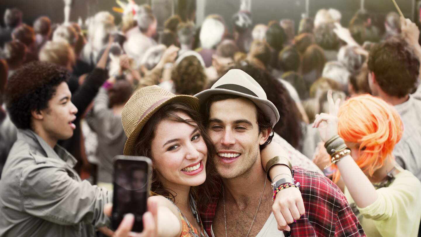 Glückliches Paar macht ein Selfie auf einem Festival. | © Gettyimages.com/Paul Bradbury