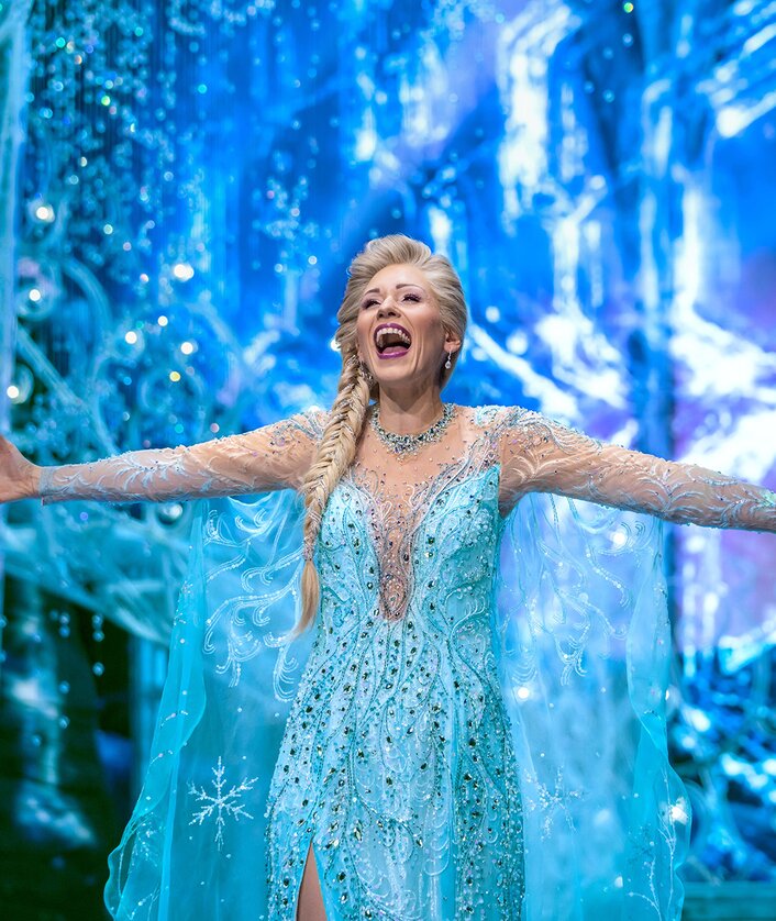 Szenenbild mit Elsa aus Disneys Die Eiskönigin – Das Musical singt auf der Bühne im blauen Kleid | © Stage Entertainment/Johan Persson