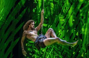 Szenenbild aus dem Musical Disneys Tarzan mit in der Luft schwingenden Tarzan im Dschungel | © Stage Entertainment/Johan Persson