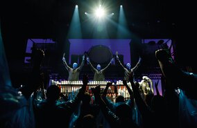 Die Blue man Group steht mit erhobenden Armen vor ihrem Publikium | © Stage Entertainment/Morris Mac Matzen