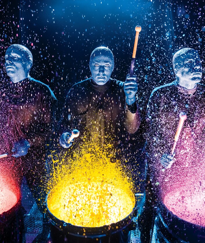 Die Blue Man Group spielt auf Farbtrommeln, Farbe spritzt durch die Gegend | © Stage Entertainment