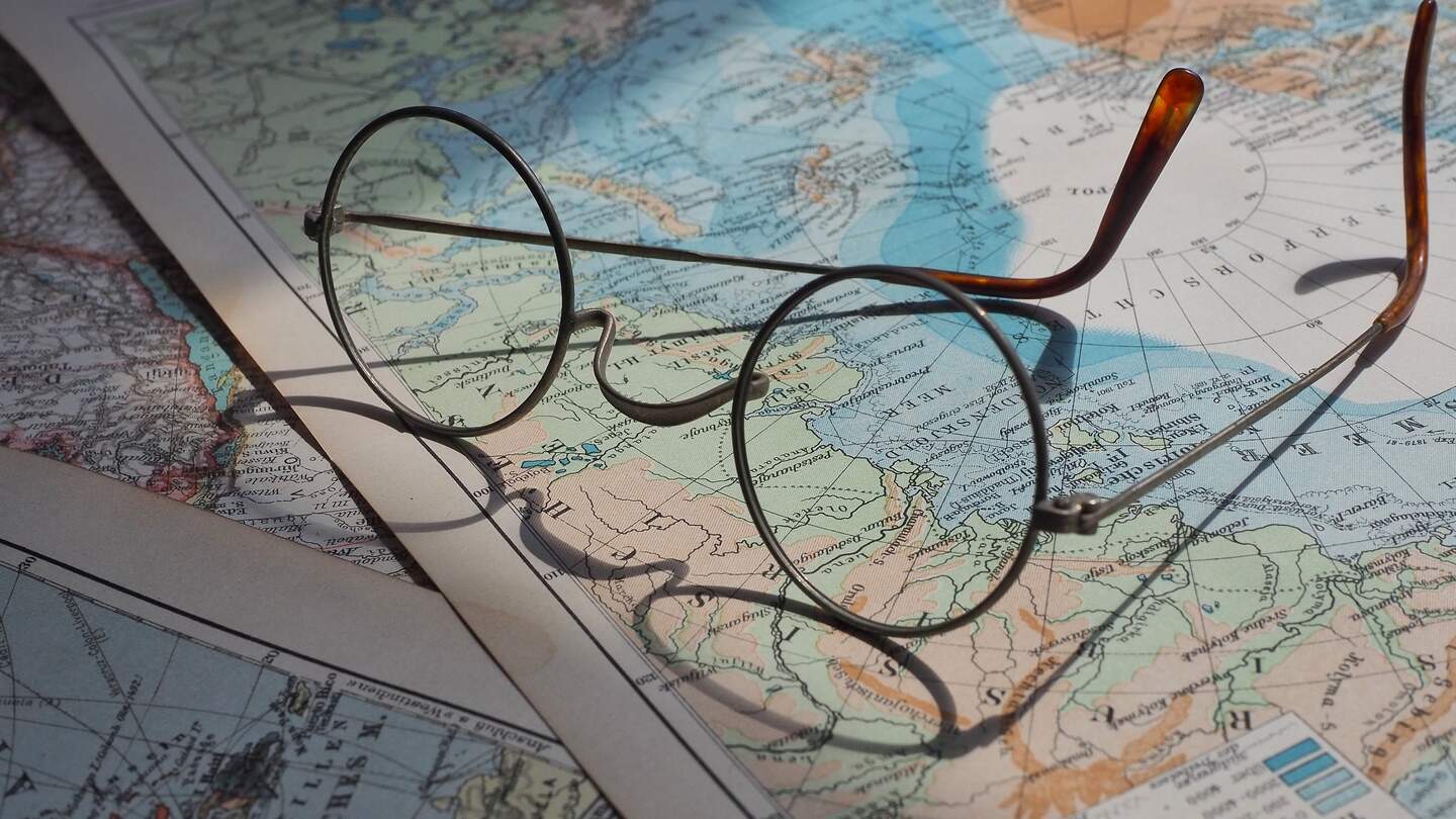 Brille liegt auf mehreren Weltkarten und wirft einen Schatten auf sie | © Pixabay/beasternchen