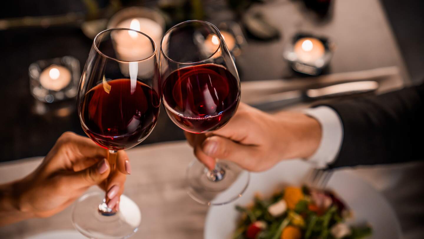 Paar stößt mit Rotwein beim Essen an | © © Gettyimages.com/Inside Creative House