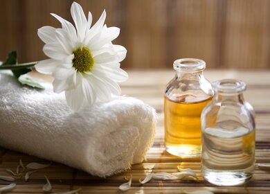 Essenzen für die Aroma-Therapie mit Handtuch und Blume | © Gettyimages.com/damircudic