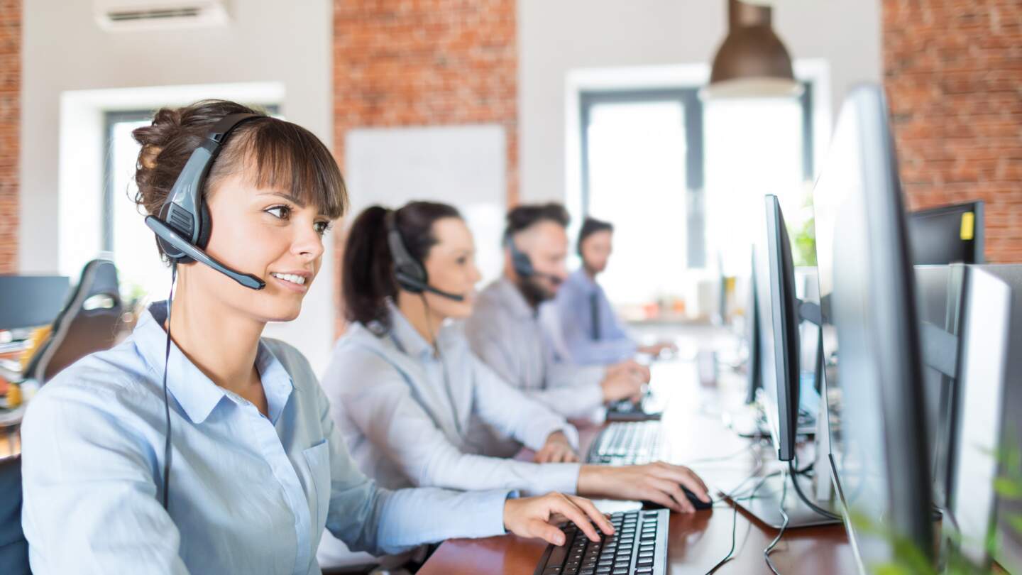 Call-Center-Mitarbeiterin in Begleitung ihres Teams | © Gettyimages.com/scyther5 Callcenterarbeitskraft von ihrem Team begleitet | © Gettyimages.com/scyther5
